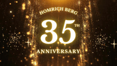 Glowing gold text reads “Homrich Berg 35th Anniversary” against a sparkling, festive golden background with falling glitter and light effects.